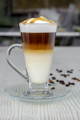 Glass of hot caramel macchiato coffee and coffe bean on table