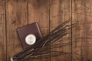 An overhead photo of a handmade broom with a candle, a grimoire, and copy space