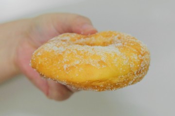 Hand Holding Delicious Glazed Donut with Sugar