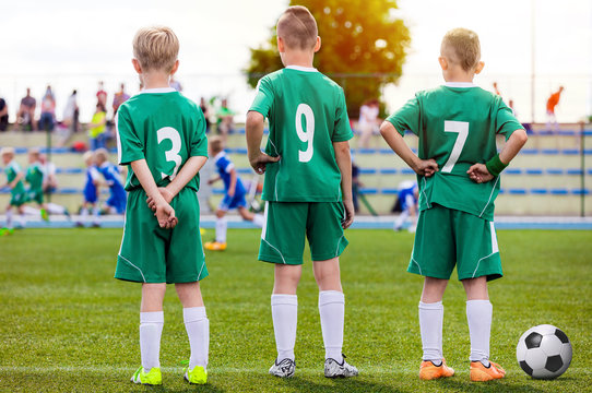 Children Football Team. Young Boys Watching Soccer Match. Football Tournament Competition in the Background. Kids Football Team Players on The Soccer Stadium