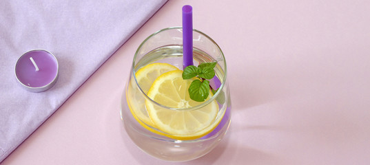 Glass of water, lemon and mint. Glass of pure water and fresh organic lemon and mint isolated on purple background. Detox and healthy food concept.