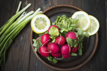 fresh radish onion and lemon on a clay plate on a wooden table, the concept of vegetarianism