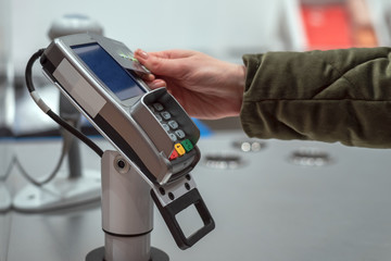 Women's hand pays for purchases in the store card contactless way, wireless technology, paypass