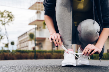 a sporty young girl assiduously trains in the open air, ties up her shoelaces on sneakers