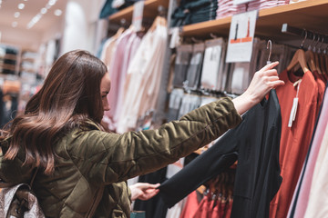A young girl walks around the store and prices for things. shopping concept