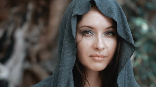 Mysterious beautiful woman with make up in grey hood
