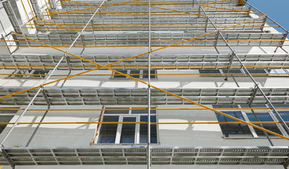 scaffolding near a new house, building exterior, construction and repair industry, white wall and window, yellow pipe