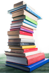 High bent tower of stacked books on wooden table