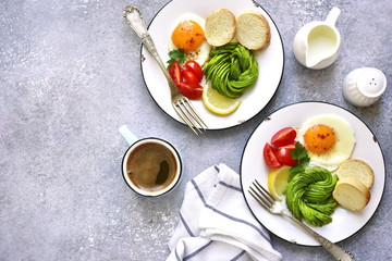 Two breakfast plates with fried egg, avocado rose and baguette.Top view.
