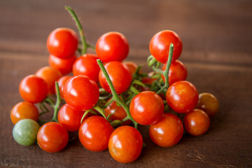 A bunch of fresh tomatoes are available on wooden floor.
