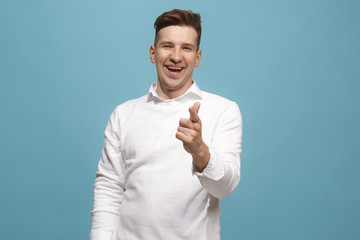 The happy business man point you and want you, half length closeup portrait on blue background.