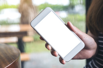 Mockup image of a hand holding white mobile phone with blank desktop screen with blur raining background