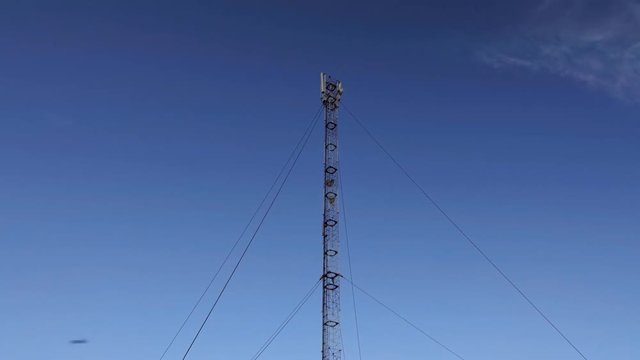GSM or CDMA Antenna on a blue sky background, timelapse.