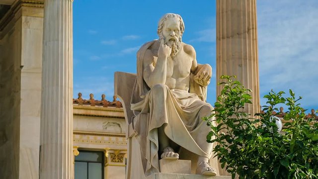 Statue of the great Greek philosopher Socrates on a marble chair, background of columns and sky, time lapse.