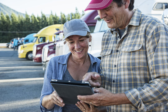 Truck driving team working on their driving log in truck stop parking lot