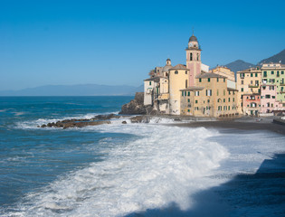 Fototapeta na wymiar Church of Camogli in a day of sea storm that overwhelms beach and pier - Genoa