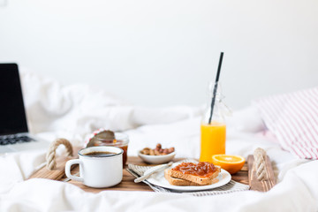 Fototapeta na wymiar Breakfast in bed. Coffee, toast with jam, fresh orange juice. View from above.