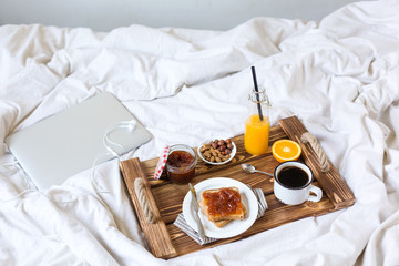 Obraz na płótnie Canvas Breakfast in bed. Coffee, toast with jam, fresh orange juice. View from above.