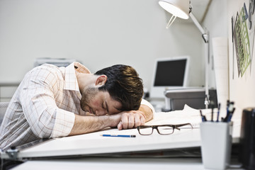 Hispanic man taking a quick nap in an architect's office.