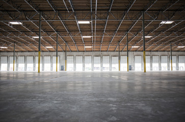 Wide angle interior view of large empty warehouse and loading dock doors