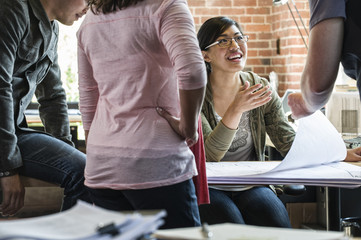 Mixed race group of people meeting to brainstorm an issue in a creative office.