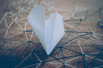 White paper plane over the threads linking the nails. Entities connected. Abstract concept (idea)...