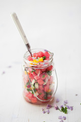 Bunter pikanter Wassermelonensalat auf weißem Holz Hintergrund