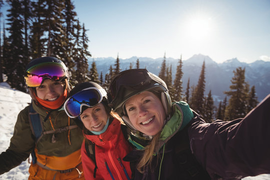 Three female skiers standing together on snow covered mountain