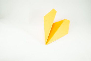 Yellow paper plane on a white background, isolated. Concept (idea) of airlines, freedom, leadership, success,  and creativity. Close-up