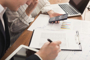 Business colleagues checking documents and using calculator