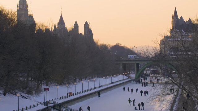 Tilt Down of Downtown Ottawa, People Ice Skating on The Rideau Canal in Winter