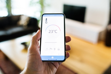 A woman holding a smartphone with smart home screen.