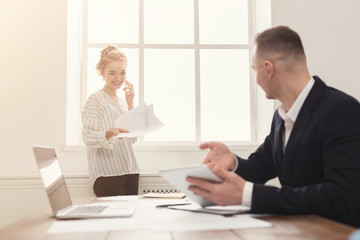 Male and female managers working on financial papers at modern office interior