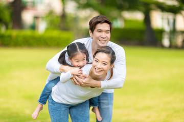 Naklejka na ściany i meble Cute Asian girl on neck parents big happy laughing and run around together.Happy family piggybacking adorable little daughter is smiling. selective focus at girl eye.