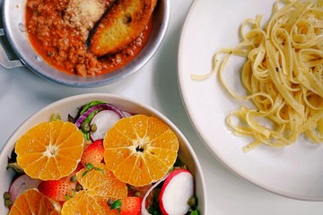 top view and close up dinner table, Italian cuisine, salad and Fettuccine Bolognese placed on white dish and a white table