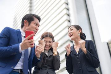 Successful Business Teamwork.Happy Young Businessmen Rising Hands Up while Their Female Colleague Smiling to Sky.