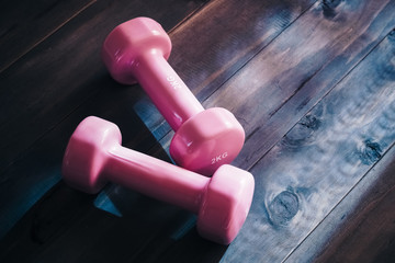Still life overhead shot of two pink dumbbells on wooden floor. Empty space for your advertising text. Healthy and active sport lifestyle concept.