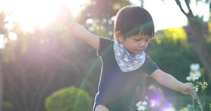cute child walking with mother in the park, mom holding hand baby boy