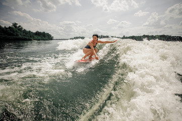 Attractive young woman wakesurfing on the board against the sky