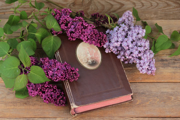 Obraz na płótnie Canvas Bouquet of lilacs and an old album on a wooden table