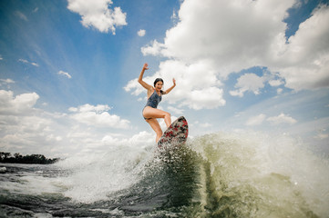Sexy slim woman having fun wakesurfing anf jumping on the board - obrazy, fototapety, plakaty