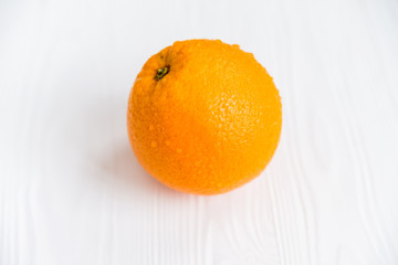 Single whole orange on white wooden surface close