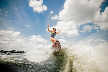 Lovely young woman having fun wakesurfing anf jumping on the board