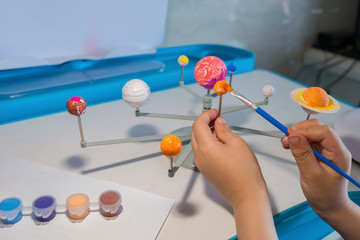 kid painting the Earth on a Solar System model