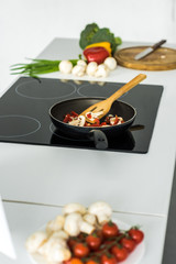 frying pan with vegetables on electric stove in kitchen