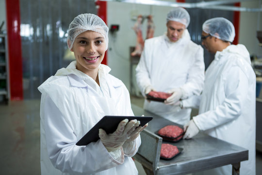 Female technician using digital tablet at meat factory