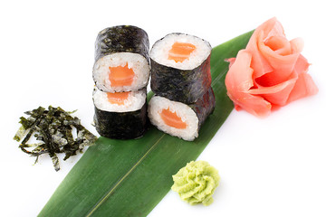 Delicious fresh mini-rolls with salmon on a banana leaf. Sushi rolls on a white background with ginger and wasabi.