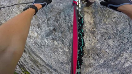 POV - a man climbs alongside a cliff in a forest and rearranges the carabiners