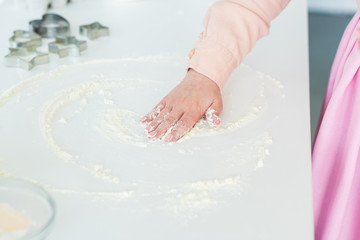 cropped image of woman spreading flour on kitchen counter