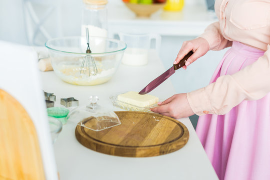 cropped image of woman cutting butter in kitchen